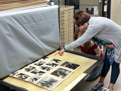 Brenda Brueggemann points to archive of black and white MTS photos as Jess Gallagher observes
