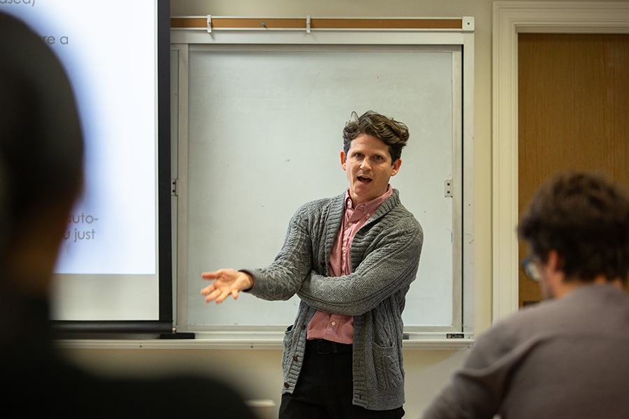 A professor speaks at front of a class.